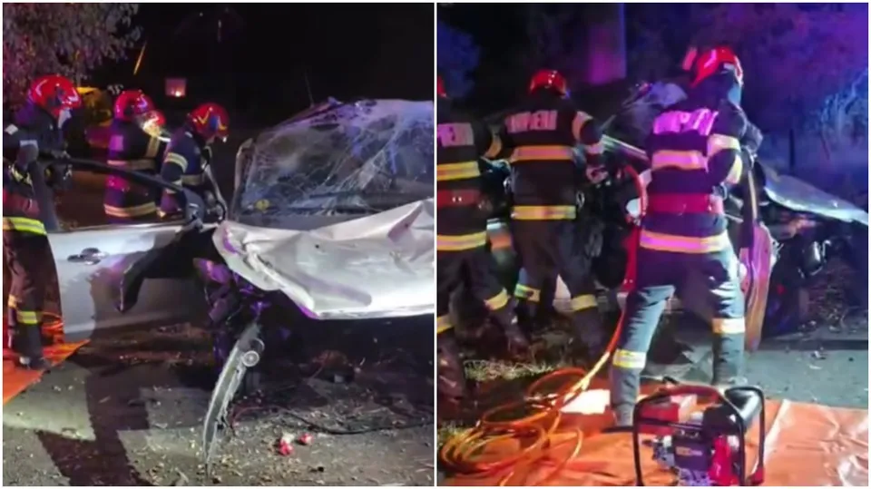 Pompieri în echipament de protecție cu benzi reflectorizante lucrează lângă un autoturism alb distrus pe un drum noaptea.