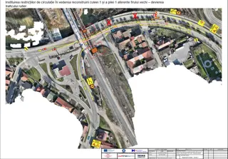 O hartă aeriană a unei zone urbane cu căi ferovare, linii galbene și marcaje roșii indicând trasee și restricții de circulație pe drumurile asfaltate.