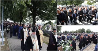 Un grup de bărbați în haine negre și vestimentație clericală merge pe un drum pavat printre copaci, în timp ce mulți oameni stau în picioare.