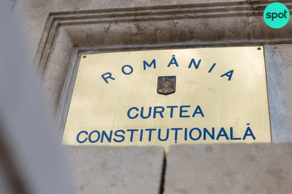 O placă metalică aurie cu textul albastru ROMÂNIA CURTEA CONSTITUȚIONALĂ este montată pe un perete de piatră.