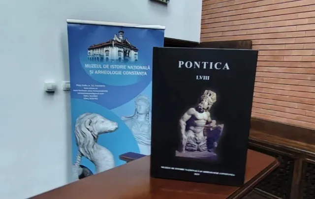 Un banner albastru cu imagini de clădiri și sculpturi stă lângă o carte neagră cu textul PONTICA LVIII pe o masă de lemn.