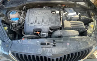 O vedere de sus asupra unui compartiment motor de mașină care conține o baterie, un rezervor de lichid și diverse componente mecanice.