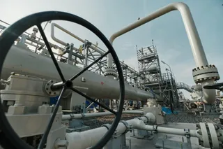 Unelte industriale și conducte metalice gri sunt situate într-o stație de procesare sub un cer senin.