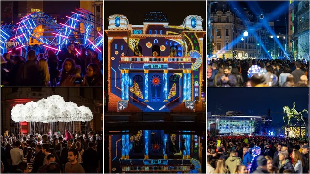 O mulțime de oameni se află pe o stradă noaptea, sub proiecții luminoase colorate pe clădiri și structuri metalice.