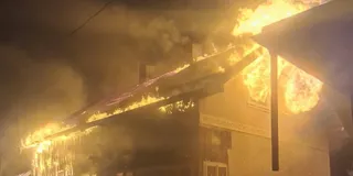 Flăcări mari și fum dens emană de pe acoperișul unei clădiri într-un cadru nocturn.