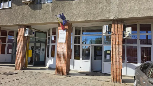 Intrarea unei clădiri cu uși de sticlă, coloane din cărămidă și un aparat de aer condiționat montat pe perete.