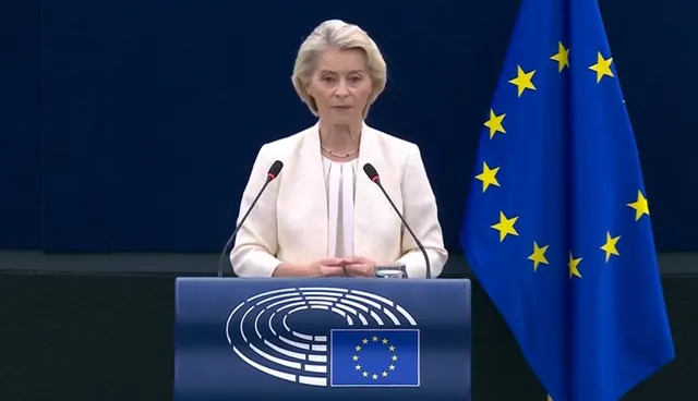 Ursula von der Leyen vorbește la un pupitru, cu steagul Uniunii Europene în dreapta sa, într-o sală de conferințe.