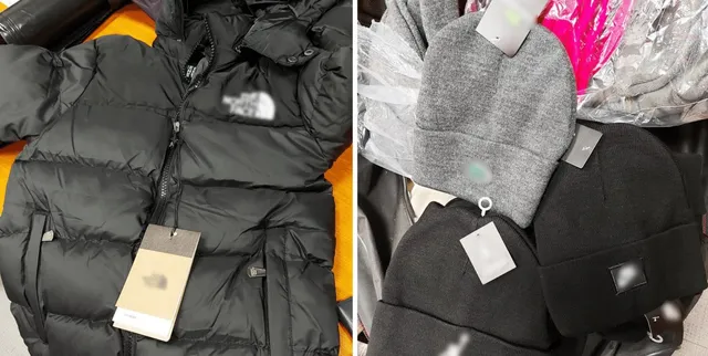 O geacă neagră de tip puf cu etichetă și trei căciuli de culori gri și negru sunt așezate pe o suprafață colorată.