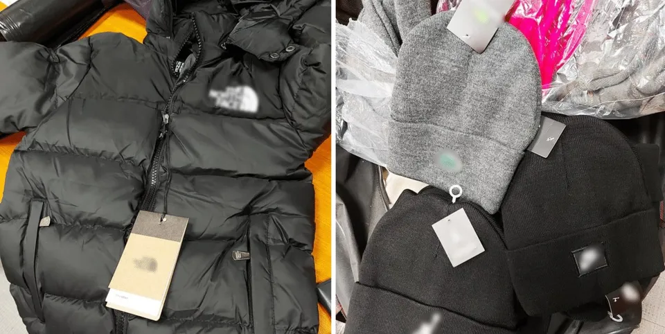 O geacă neagră de tip puf cu etichetă și trei căciuli de culori gri și negru sunt așezate pe o suprafață colorată.