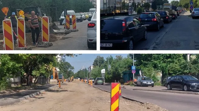 Un lucrător stă lângă conuri de circulație și un utilaj de construcții pe un drum cu șantier, lângă mașini parcate pe o stradă.