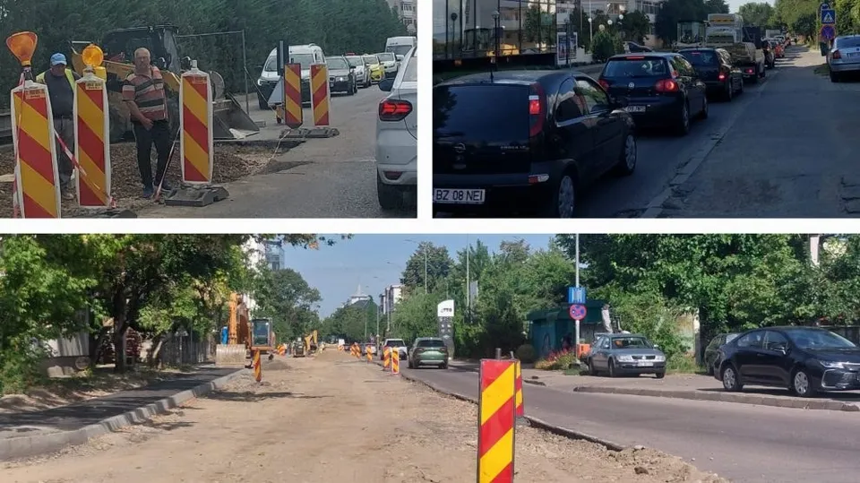 Un lucrător stă lângă conuri de circulație și un utilaj de construcții pe un drum cu șantier, lângă mașini parcate pe o stradă.
