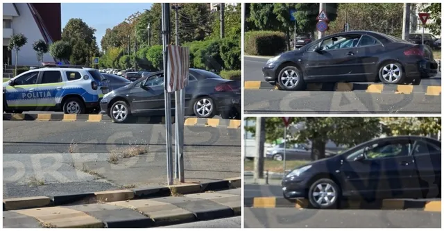 Un autoturism negru este poziționat pe bordura unei insule de separare, lângă un vehicul de poliție albastru și alb.