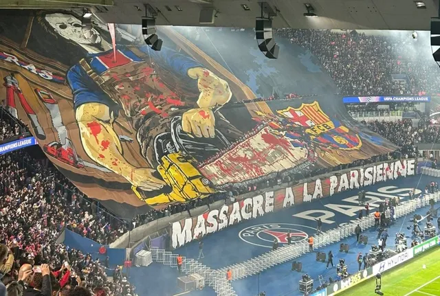 Un banner mare cu o ilustrație de groază și textul MASSARE A LA PARISIENNE este întins deasupra tribunelor unui stadion de fotbal.