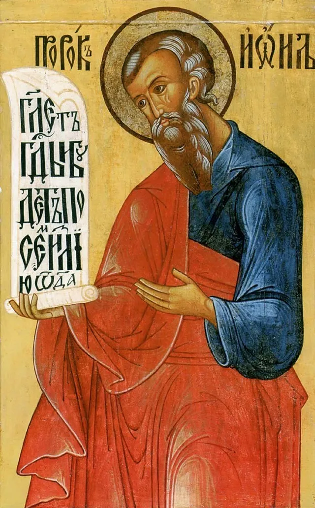 O pictură religioasă reprezintă un bărbat cu barbă cărățând un pergament alb cu inscripții negre pe un fundal auriu.