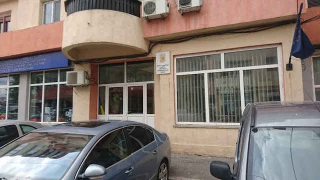 O clădire cu ferestre mari, unități de aer condiționat montate pe perete și două mașini parcate în prim-plan.