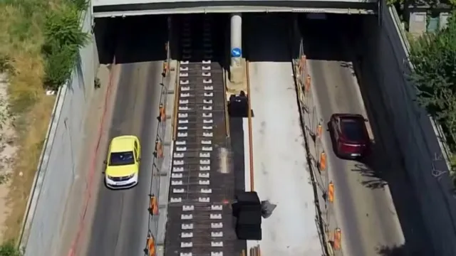 O vedere de sus prezintă două benzi de circulație separate de șine de tramvai, cu un autoturism galben și unul roșu pe drumuri.