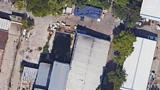 O vedere aeriană prezintă diverse clădiri cu acoperișuri plate și înclinate, un teren de beton și vegetație dispersată între structuri.