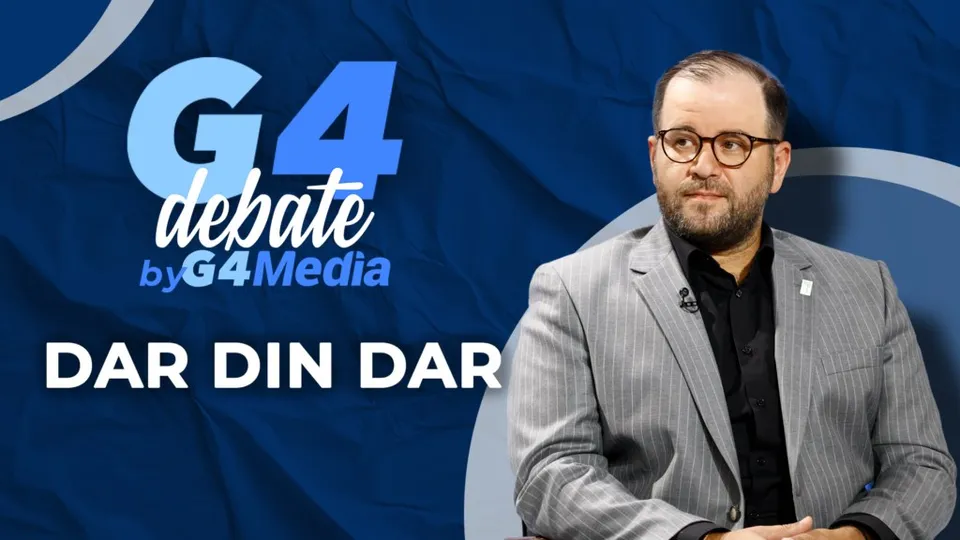 Un bărbat cu ochelari și sacou gri stă în fața unui fundal albastru pe care scrie textul G4 debate by G4Media și DAR DIN DAR.