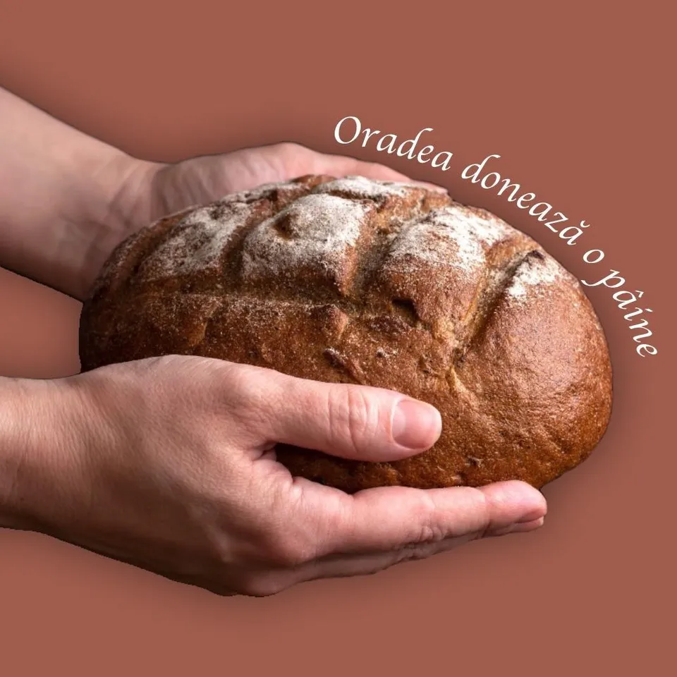 Două mâini țin o pâine rotundă, coaptă, pe un fundal de culoare maro.