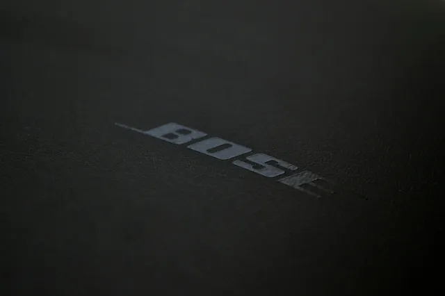 Logo-ul cu textul BOSE este imprimat pe o suprafață neagră, texturată și mată.