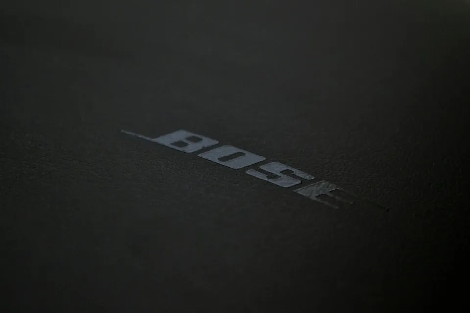 Logo-ul cu textul BOSE este imprimat pe o suprafață neagră, texturată și mată.