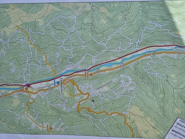 O hartă topografică detaliată prezintă linii de contur, drumuri colorate și zone verzi pe un fundal de relief montan.
