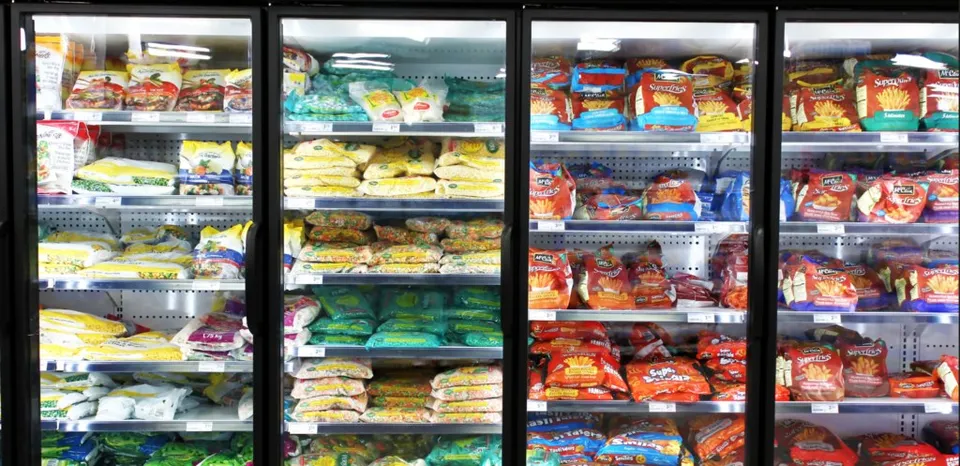 Patru vitrine frigorifice cu rafturi pline de produse alimentare ambalate în pungi și cutii sunt aliniate vertical.