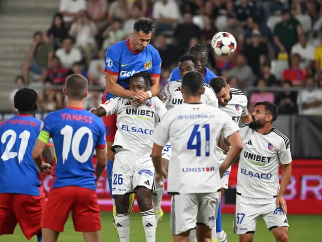 Jucători de fotbal în tricouri albastre și albe, unul sărind pentru a capta mingea într-un meci.