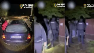 O mașină închisă la culoare este parcată pe un drum, în timp ce mai mulți oameni în uniformă stau în apropiere pe timp de noapte.