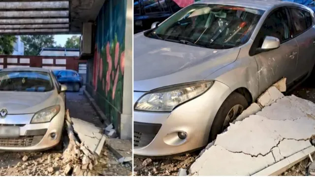 O mașină de culoare argintie este parcată lângă resturi de beton și piese de structură prăbușite pe un trotuar.