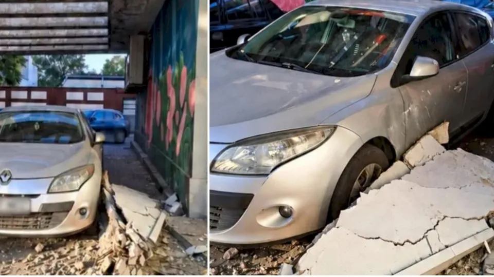 O mașină de culoare argintie este parcată lângă resturi de beton și piese de structură prăbușite pe un trotuar.