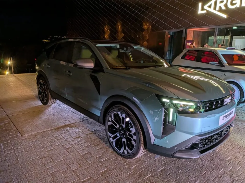 Un crossover de culoare gri este parcat pe un pavaj lângă o clădire iluminată noaptea.