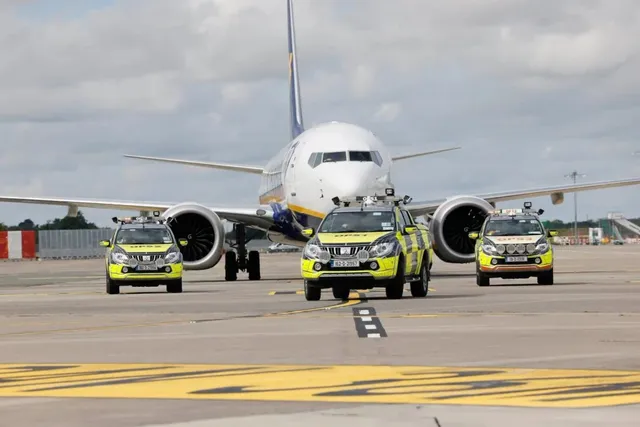 Un avion de pasageri alb stă pe o pistă de aeroport în spatele a trei mașini de poliție de culoare galbenă și gri.