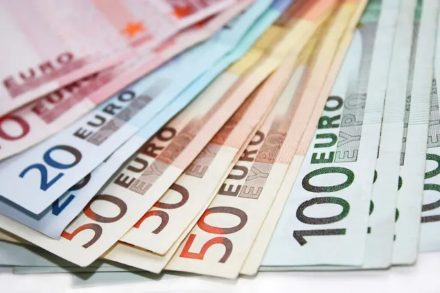 Mai multe bancnote de euro de diferite valori sunt întinse în evantai pe o suprafață albă.