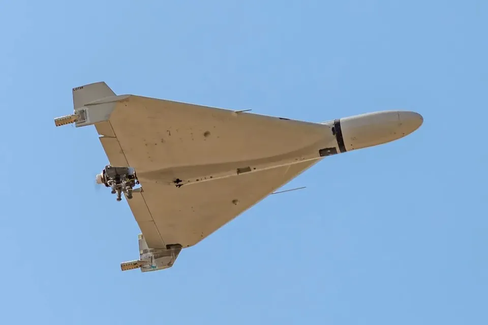 Un avion fără elicoptere de culoare gri zboară pe un cer albastru luminos.
