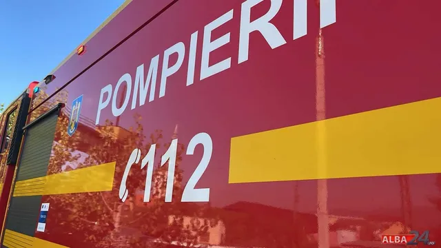 Partea laterală a unui vehicul roșu pe care sunt scrise cuvintele POMPIERII și numărul 112, având o dungă galbenă orizontală.