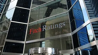 O clădire modernă cu fațadă de sticlă prezintă un logo cu textul Fitch Ratings aplicat pe suprafața transparentă.