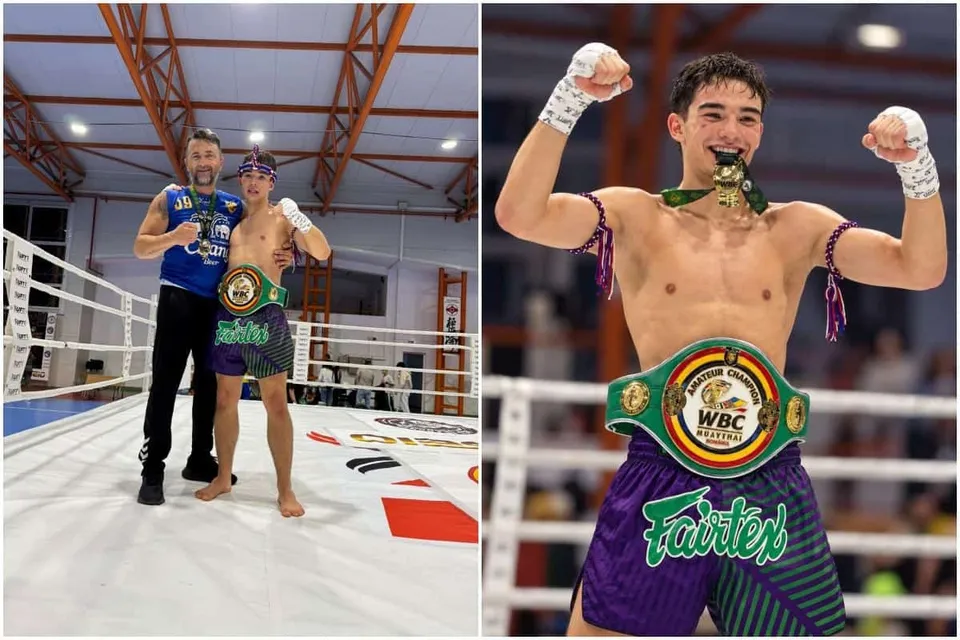 Un bărbat fără tricou poartă un centură verde și purtări de protecție albe, ridicând brațele în timp ce stă într-un ring de luptă.