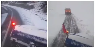 Vehiculul acoperit cu zăpadă are luminile roșii aprinse pe un drum înzăpezit, în timp ce un autovehicul galben deszăpezește drumul în față.