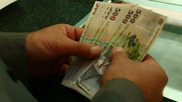 Două mâini țin un teanc de bancnote de cincicinci sute de lei.