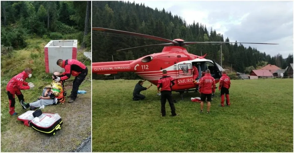 O echipă de salvatori în uniforme roșii stă lângă un elicopter roșu aterizat pe o iarbă, în timp ce alți salvatori asistă o persoană întinsă pe sol.
