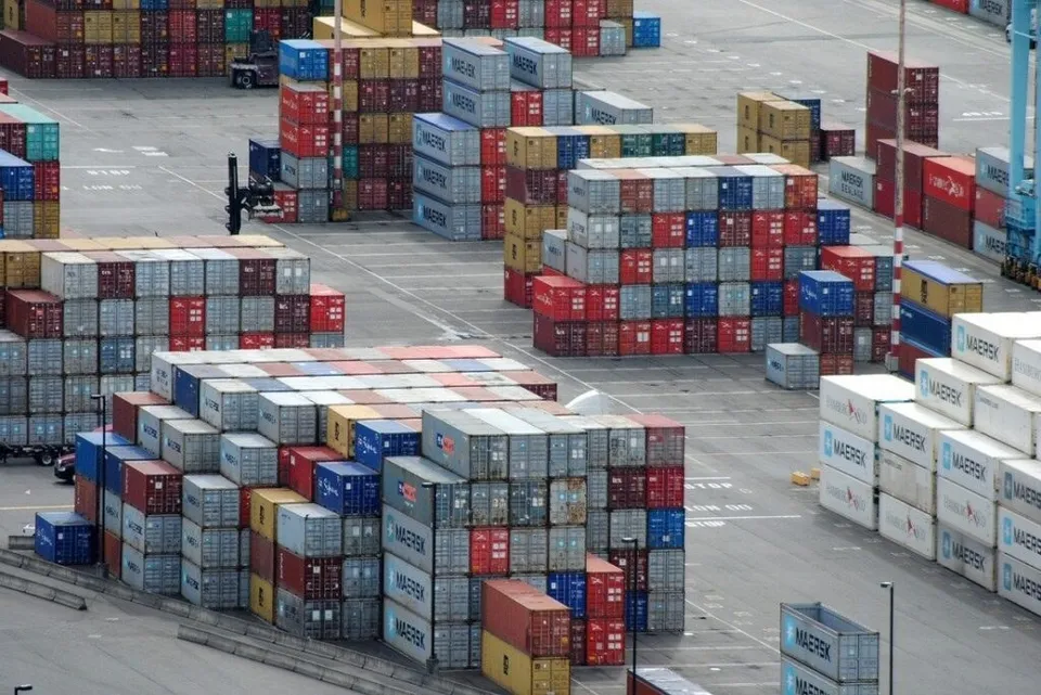 Multe containere colorate sunt stivuite în grupuri mari pe o suprafață de asfalt într-un port.