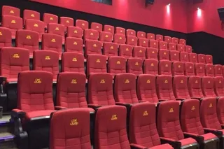 Rânduri de scaune roșii de cinema dispuse în trepte într-o sală de proiecție.