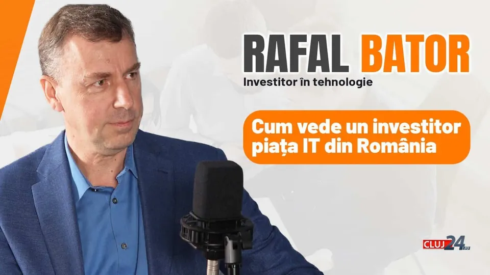 Un bărbat cu sacou albastru și cămașă albastră stă lângă un microfon negru pe un fundal cu text și grafică portocalie.