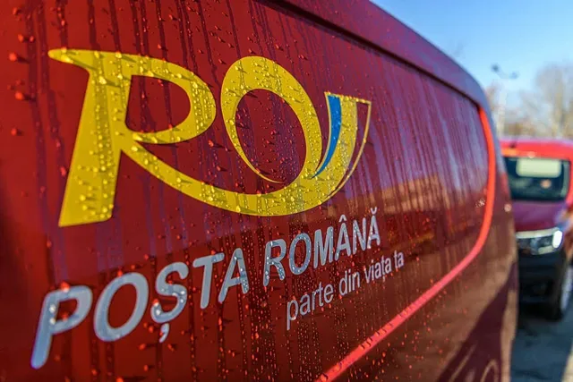 Un logo galben pe un vehicul roșu acoperit de picături de apă, cu textul alb POȘTA ROMÂNĂ scris sub acesta.
