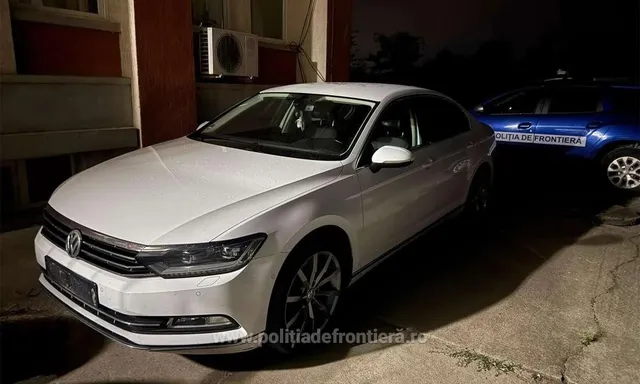 Un autoturism alb este parcat pe un drum lângă o clădire, în apropierea unui vehicul albastru pe care scrie poliția de frontieră.