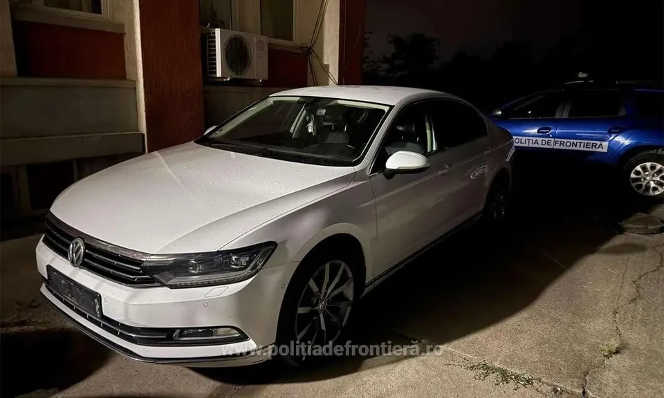 Un autoturism alb este parcat pe un drum lângă o clădire, în apropierea unui vehicul albastru pe care scrie poliția de frontieră.