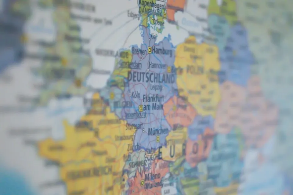 O hartă colorată a Europei prezintă diverse țări și orașe precum Deutschland, Frankfurt și München pe un fundal neclar.