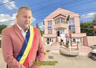 Un bărbat cu sacou roz și o bandă tricoloră poartă haine formale în fața unei clădiri cu ferestre mari și scări exterioare.