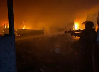 Silueta unui soldat cu o armă este vizibilă în prim-plan, în fața unui incendiu intens care luminează un teren de noapte.